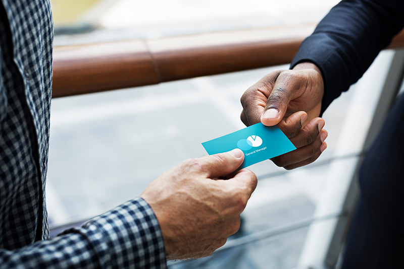 Professionals exchanging custom business cards at a networking event, highlighting the importance of personal branding. 